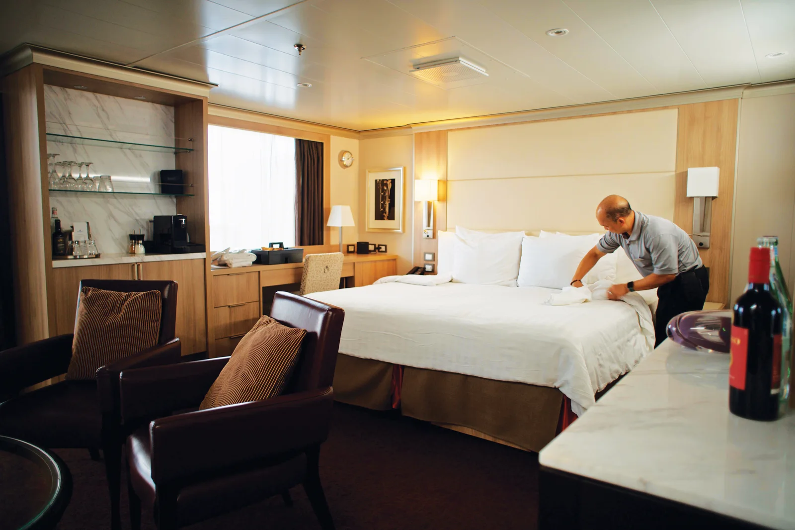 Steward turning down the bed in a Holland America Neptune Suite